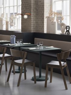 an empty restaurant with tables and chairs in front of large windows, along with vases on the wall