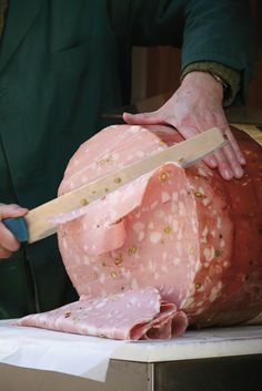 a man cutting up a large piece of meat on top of a table with a knife