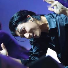 a man with black hair and piercings standing in front of a crowd at a concert