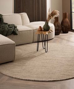 a living room with a round rug on the floor and two vases next to it