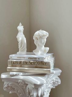 there are three books stacked on top of each other in this white vase with two busturines