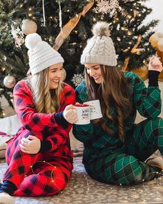 two young women sitting on the floor in pajamas and hats, one holding a mug