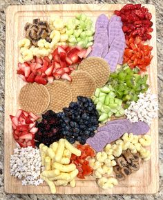 a wooden board topped with lots of different types of fruits and vegtables