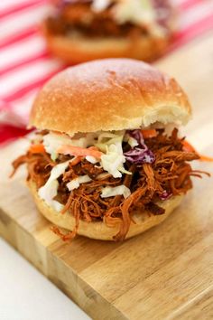 a pulled pork sandwich with cole slaw on a wooden cutting board