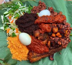 an assortment of food is displayed on a leafy platter with eggs, meats and vegetables