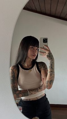 a woman taking a selfie in front of a mirror with tattoos on her arm