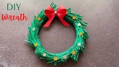 a christmas wreath made out of green yarn and red ribbon with the words diy wreath on it