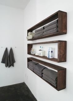 two wooden shelves holding towels and other bathroom items