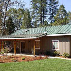 a small building with a green roof and trees in the background