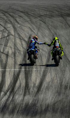 two people riding motorcycles on a race track