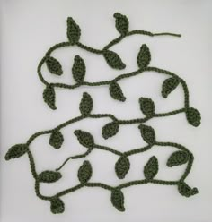 crocheted leaves are arranged in the shape of a tree on a white surface