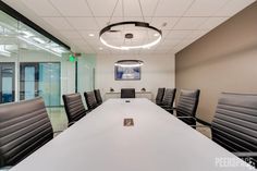 an empty conference room with black chairs and a white table in front of glass walls