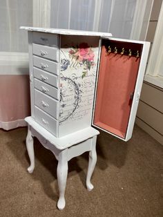 a white cabinet with drawers sitting on top of a carpeted floor next to a window