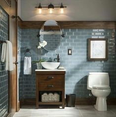 a bathroom with blue brick wall and white toilet, sink and mirror on the wall