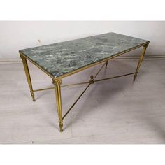 a green marble top coffee table with gold frame and metal legs, sitting on a white tile floor