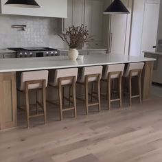 a large kitchen with an island and bar stools next to it on the hardwood flooring