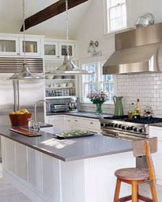 a kitchen with white cabinets and stainless steel counter tops, along with an island in the middle