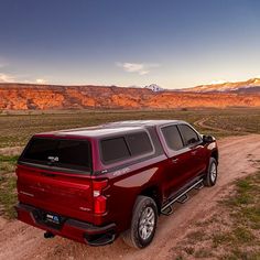 a red truck is parked on a dirt road