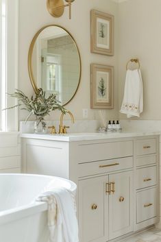 a bathroom with a tub, mirror and pictures on the wall