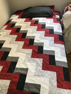 a bed with a red and black quilt on it