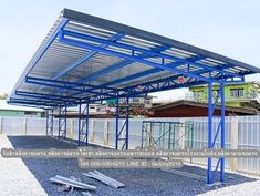 a blue metal structure sitting on top of gravel next to a white fence and green building