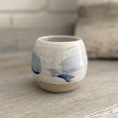 a white and blue vase sitting on top of a wooden table