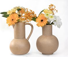 two vases with yellow and white flowers in them on a white background, side by side