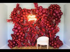 a white chair sitting in front of a wall covered with red balls and balloons that say happy new year