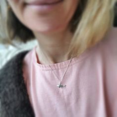 a woman wearing a pink shirt and a necklace with a silver bird on it's neck