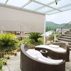 an outdoor living area with furniture and plants on the deck, covered in white shades