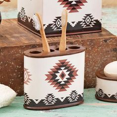 two toothbrushes and one brush in a holder sitting on a wooden table next to other items