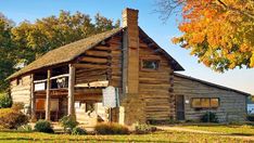 an old log cabin sits in the grass