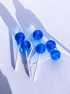 several blue lollipops are on a white surface