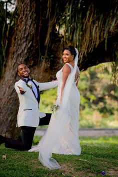 a bride and groom posing for a photo under a tree