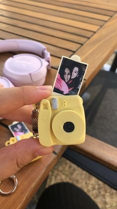 a person holding up a yellow camera with a picture on it's front and side