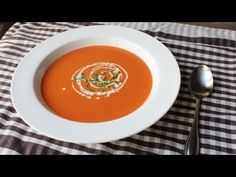 a bowl of tomato soup on a checkered table cloth