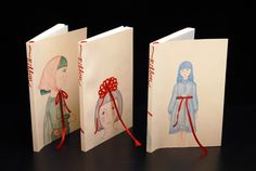 three greeting cards with children's drawings on them, one in red ribbon and the other in blue