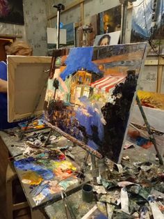 an artist's easel is covered with paint and other art supplies in the background