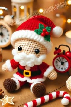 a crocheted santa clause doll sitting next to a clock and candy cane on a table