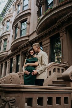 a man and woman are standing on the steps in front of an old brownstone building