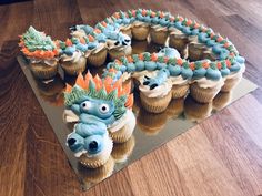 cupcakes with frosting and decorations are arranged in the shape of a dragon