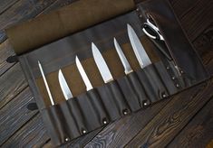 five knives in a leather case on a wooden table