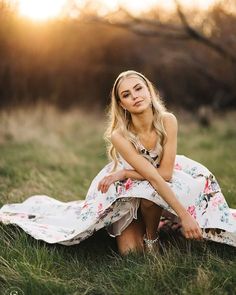 a beautiful blonde woman sitting in the grass