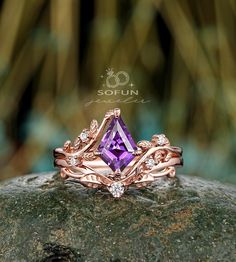 a ring with an amethorate and diamonds on it sitting on top of a rock