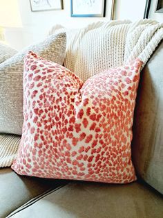 a close up of a pillow on a couch in a room with pictures on the wall