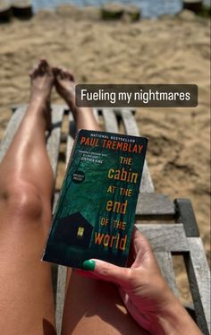 a person sitting on a bench holding a book in front of their legs with the words paul tremblay, the cabin at the end of the world