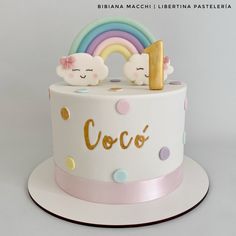 there is a white cake with rainbows and clouds on the top that says coco