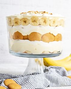 an image of a cake with bananas and cream frosting on the top in a glass dish