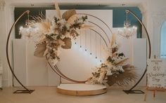 a wedding arch decorated with white flowers and greenery in the middle of a room