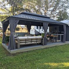 a covered patio area with tables and chairs in the grass next to an rv park